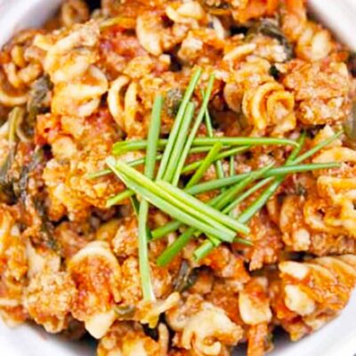 An overhead view of this Superfood Rotini Recipe, looking down into the bowl of pasta. It's garnished with fresh chives.