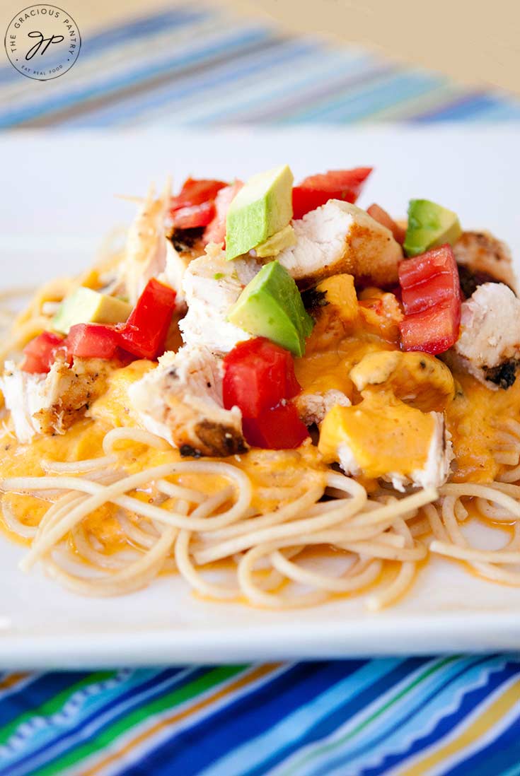A plate of pasta piled high with whole grain noodles, plenty of cheesy alfredo sauce, delicious chunks of chicken and of course, some Tex Mex toppings like tomatoes and avocados. Yum!