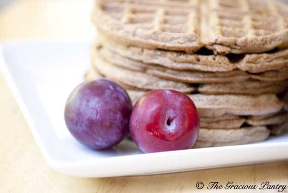 A stack of gingerbread waffles on a white, square plate.