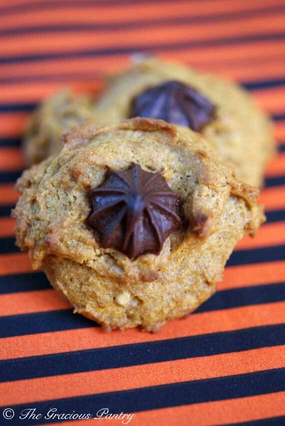 Two Chocolate Chip Walnut Pumpkin Cookies on a orange and black stripped background.