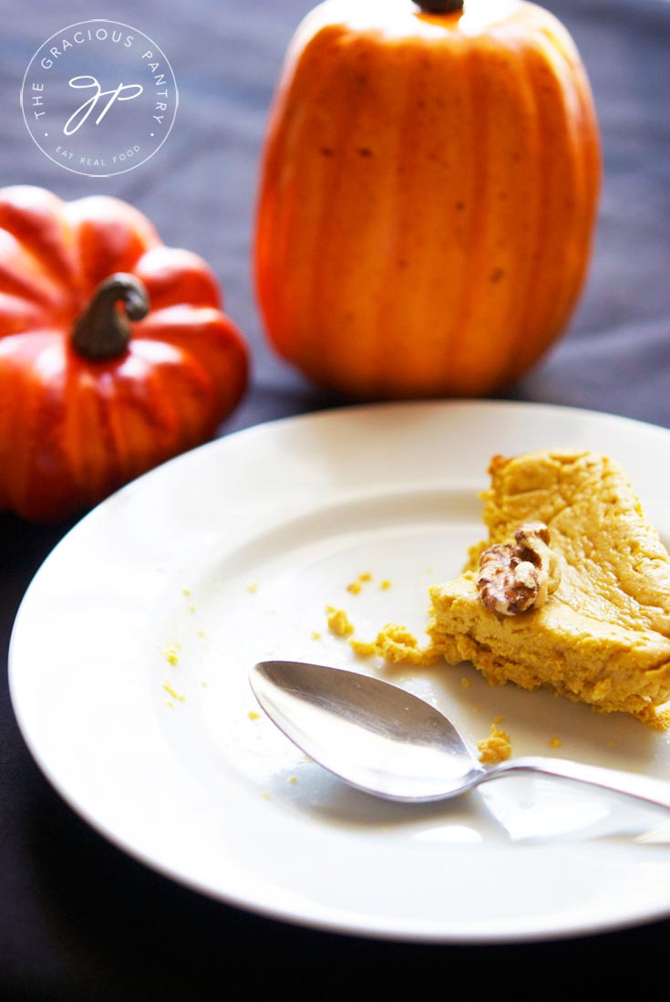 A slice of half-eaten Healthy Pumpkin Cheesecake on a white plate with a spoon.