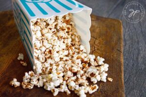 Finished kettle corn served in a popcorn container, laying on its side.