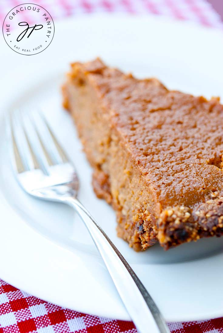 A slice of this Sweet Potato Pie Recipe sits on a white plate with a fork next to it, ready to enjoy.