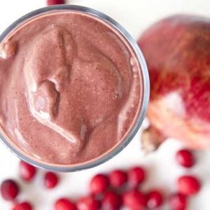 An overhead view of a chocolate cranberry smoothie in a glass on a white surface.