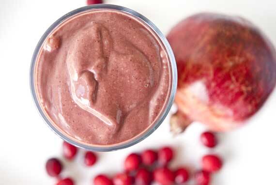 An overhead view of a chocolate cranberry smoothie in a glass on a white surface.