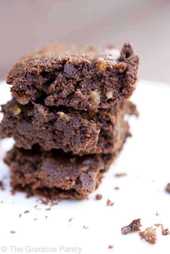 Three of these Clean Eating Freedom Brownies are stacked on top of each other on a round, white plate.