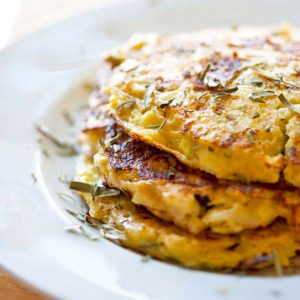 A white plate stacked with three Cauliflower Fritters.