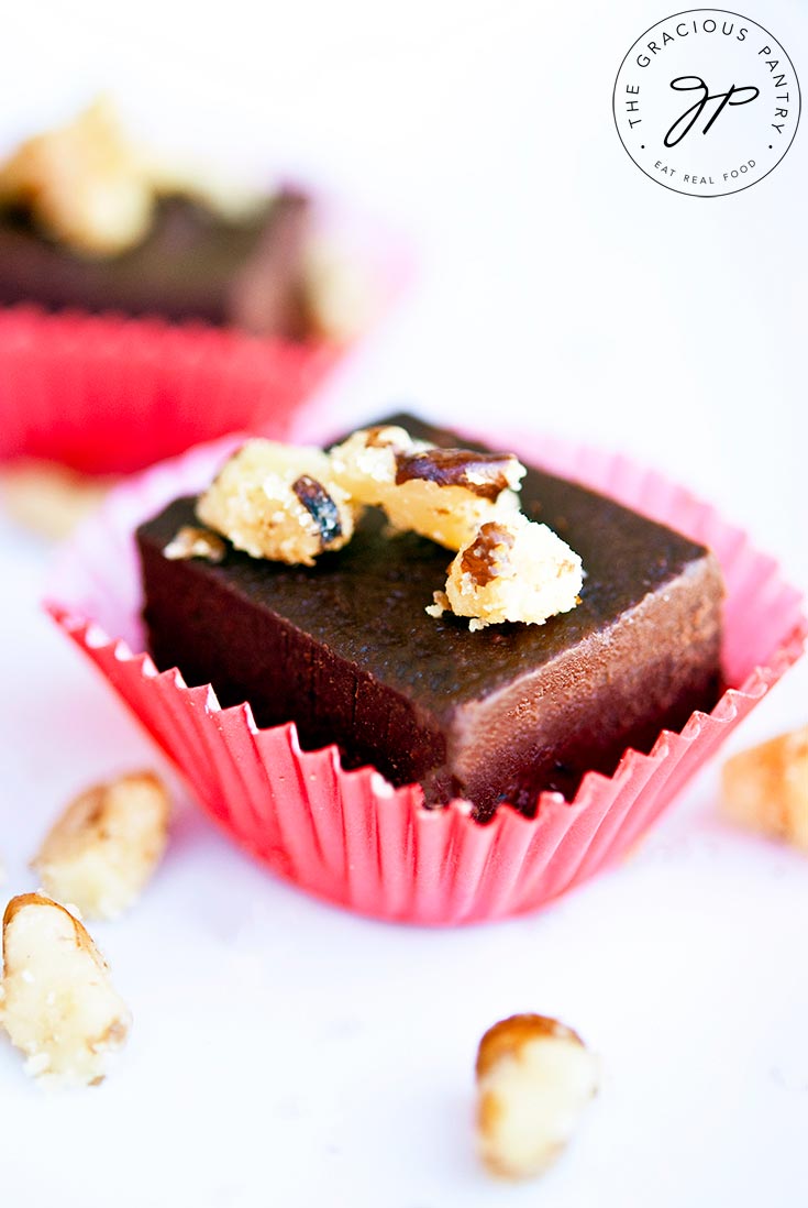 A close up of a single piece of Clean Eating Banana Walnut Fudge sitting in a red, cupcake liner.