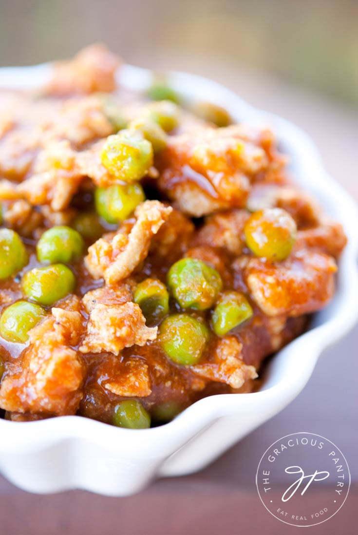 Clean Eating Coconut Curry Turkey Chili shown up close in a white bowl. You can see the bits of chili in red sauce with peas throughout.