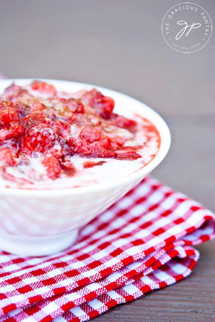 A bowl of this Strawberry Fool Recipe sits topped with some fresh, crushed strawberries.