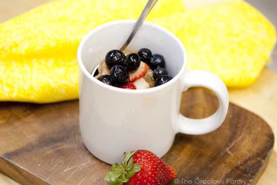 A single white mug with a microwave pancake in it sits on a wood cutting board.