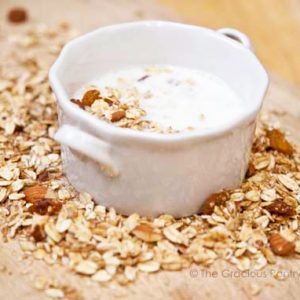 A small white bowl filled with milk and cold cereal.