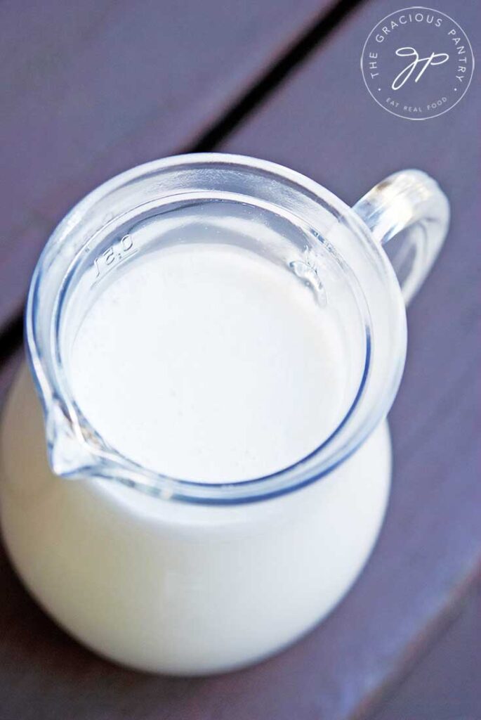A pitcher of fresh almond milk sits on a table, ready to pour in this guide, how to make almond milk.