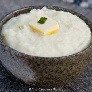 A bowl filled with holiday mashed potatoes and topped with a pat of butter.