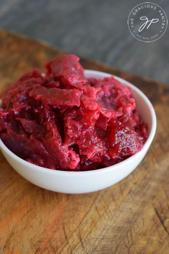 Thicker Slow Cooker Cranberry Sauce in a white serving dish sitting on a wooden surface.