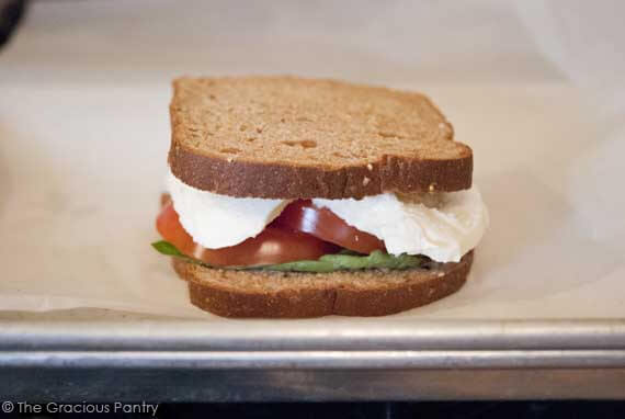 An assembled grownup grilled cheese sandwich sitting on a parchment-lined baking pan.