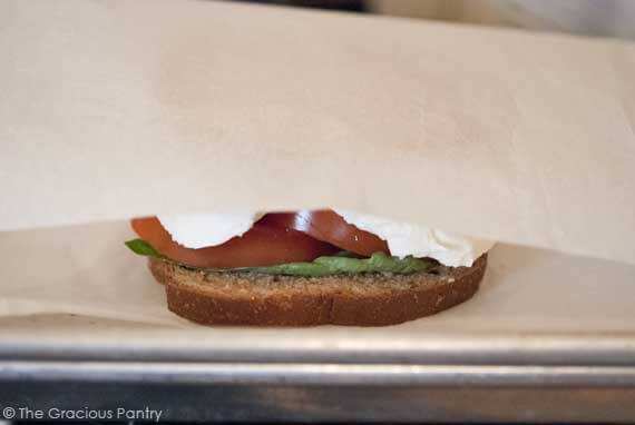 A grownup grilled cheese sandwich between parchment paper.