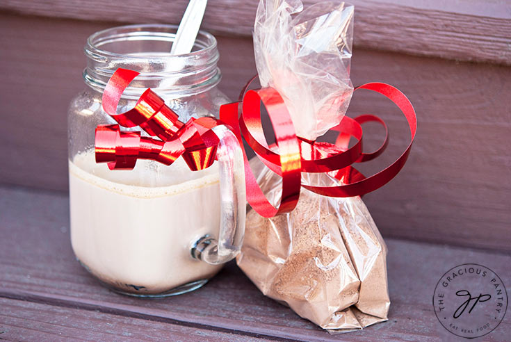 A horizontal image of a mug with hot chocolate in it and a bag of Homemade Hot Chocolate Mix sitting next to it.