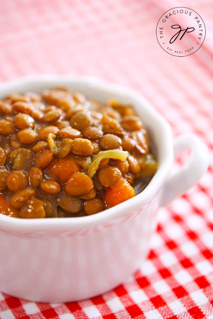 Clean Eating Slow Cooker Lentil Soup recipe in a white bowl. Amid the cooked lentils, you can also see bits of carrot and celery.