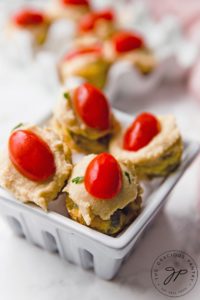 A set of four quiches from this Mini Quiche Recipe. They are set in a ceramic basket and you can see more in an egg carton sitting behind that.