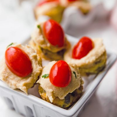 A set of four quiches from this Mini Quiche Recipe. They are set in a ceramic basket and you can see more in an egg carton sitting behind that.