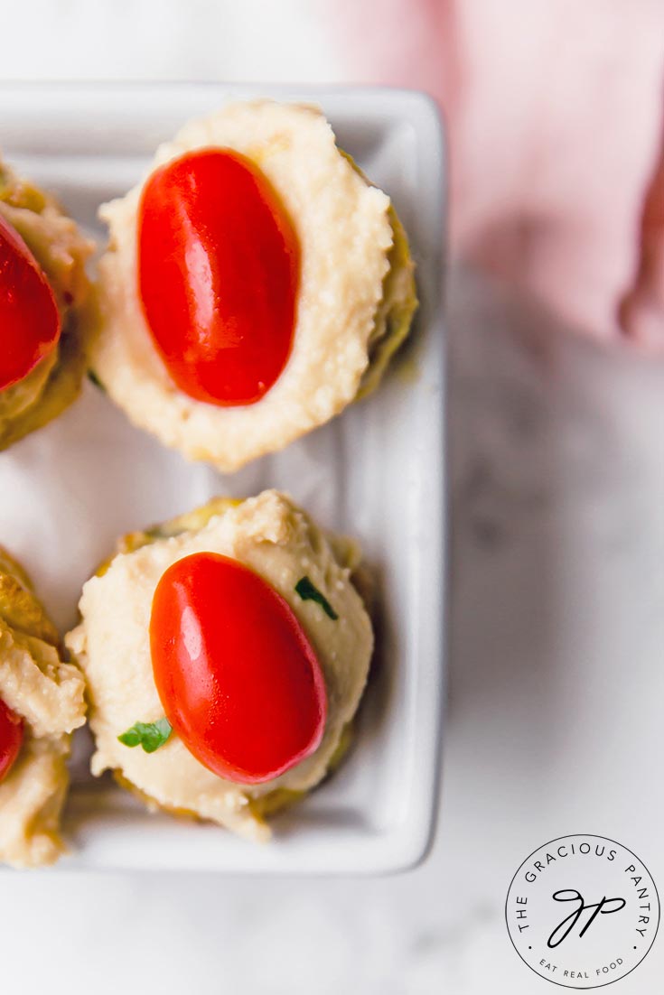 An overhead view of four quiches from this Mini Quiche Recipe. You can see the hummus and half a grape tomato on top of each quiche.