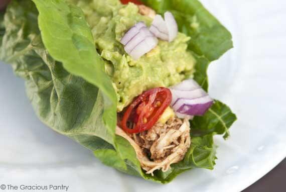 These Clean Eating Slow Cooker Low Carb Tacos let you enjoy tacos with far fewer carbs. Image shows the taco ingredients wrapped up in a lettuce wrap, open from the side so you can see inside.