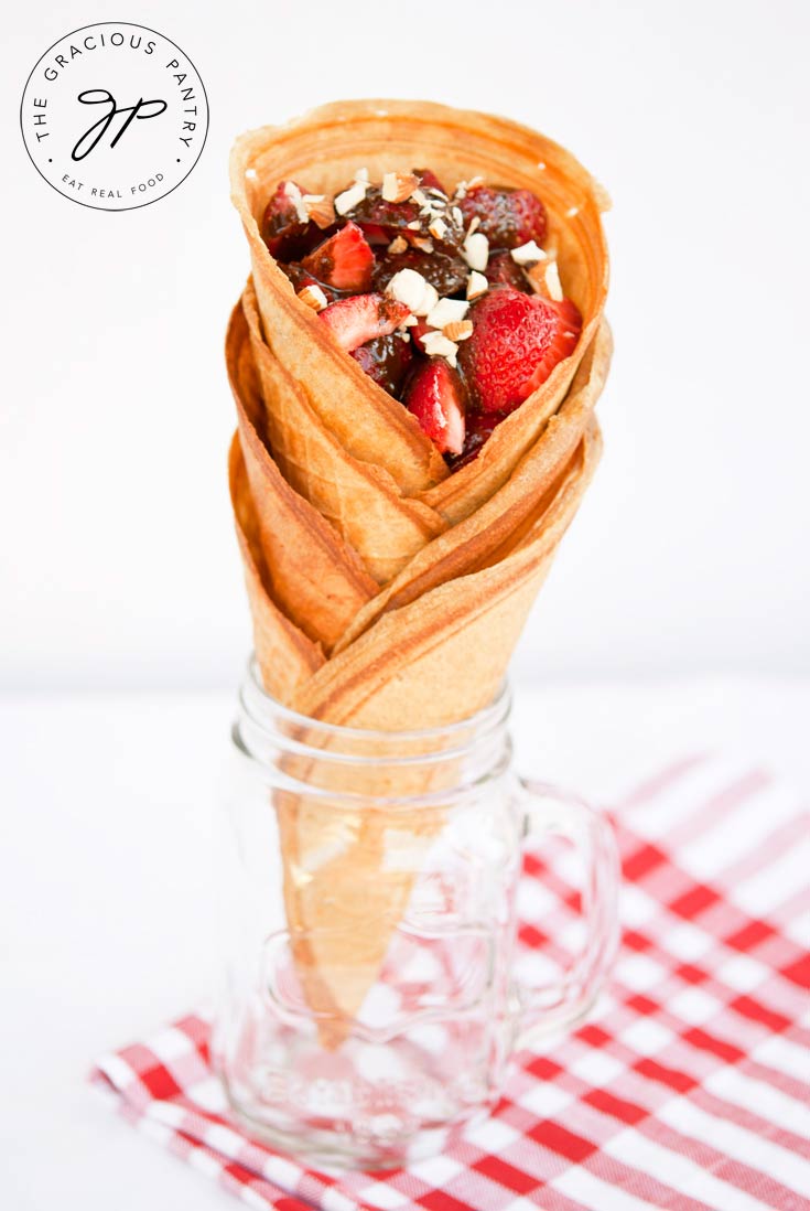 The same stack of Clean Eating Waffle Cones shown head on. There is a white and red checkered cloth under the jar and you can clearly see the layers of stacked cones.