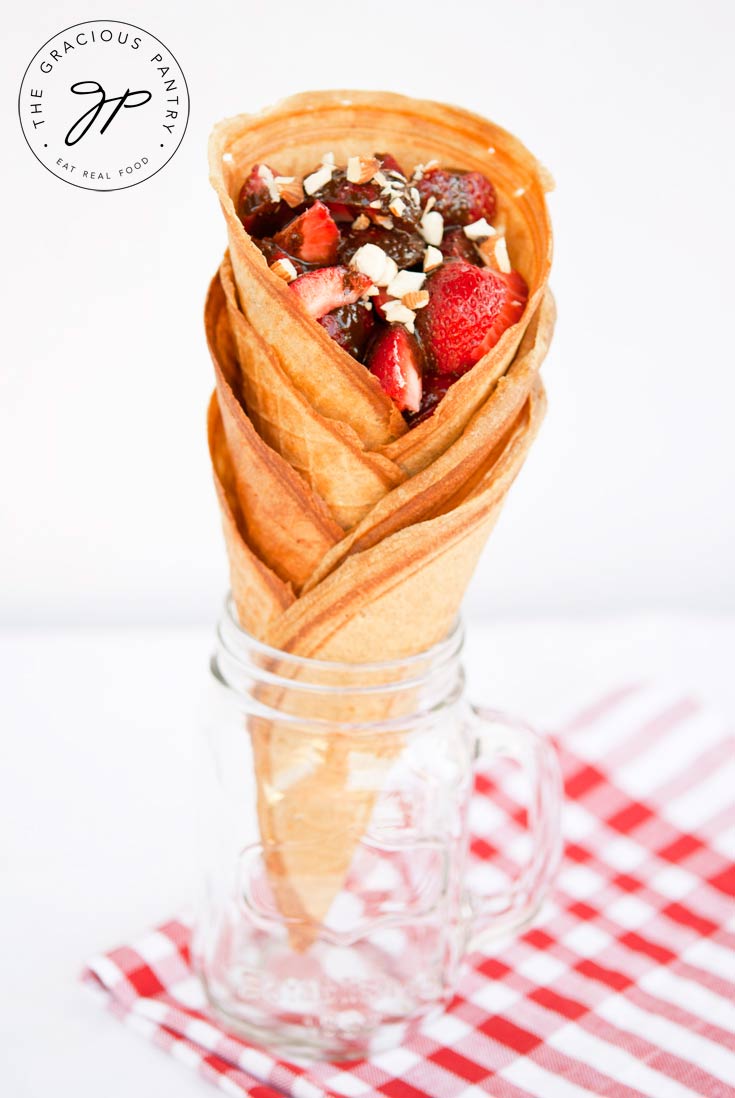 The same stack of Clean Eating Waffle Cones shown head on. There is a white and red checkered cloth under the jar and you can clearly see the layers of stacked cones.