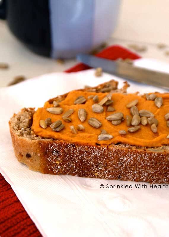 A slice of toast with hummus and sunflower seed on top.