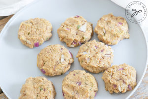 Formed raw tuna patties sit on a white plate, ready to be cooked.