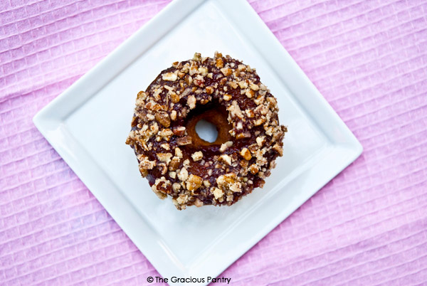 An overhead shot of a single doughnut from this Clean Eating Doughnuts Recipe. It's the same doughnut as above, just looking down from the top. You can see the red fruit spread and chopped nuts over the top of the doughnut.