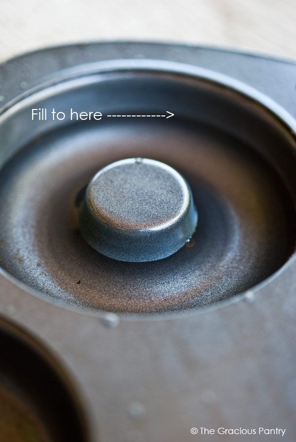 A closeup of a well in a donut pan filled with water to show where to fill the well to with batter.