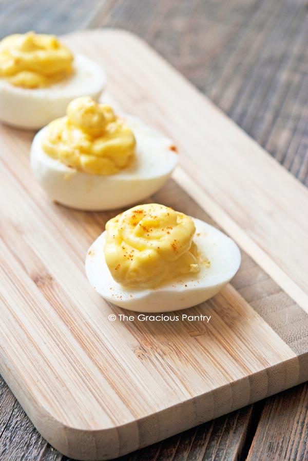 3 deviled eggs lined up on a cutting board.