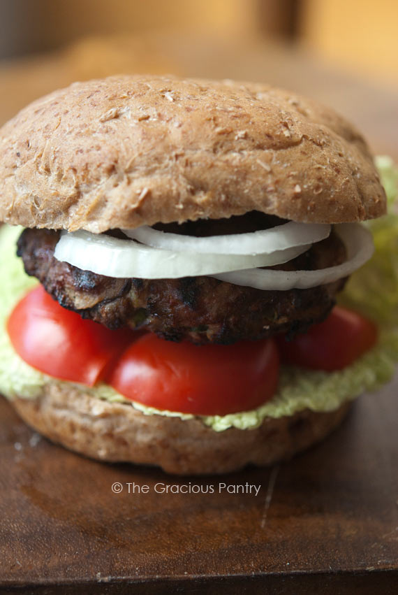 An up close view of these Clean Eating Shiitake Mushroom Burgers. You can see a single burger with each layer being visible. The bun, burger, onions, tomato and lettuce.