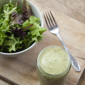 mason jar of avocado lime ranch dressing next to garden salad