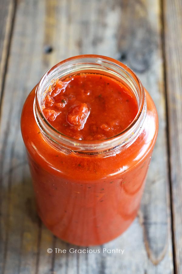 A clear, glass jar of Clean Eating Spaghetti Sauce with its lid off.