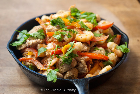 Barbecued Southwestern Chicken And Shrimp Skillet in a cast iron skillet on a wood surface.