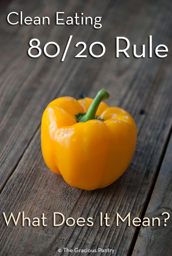 A single yellow bell pepper sits on a wooden table in this post on The Clean Eating 80/20 Rule