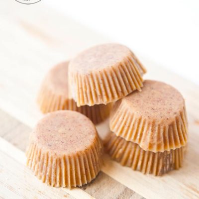 Five of these Clean Eating Peanut Butter Fat Bombs sit on a cutting board, ready to eat.