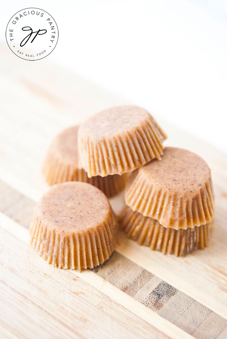 Five of these Clean Eating Peanut Butter Fat Bombs sit on a cutting board, ready to eat.