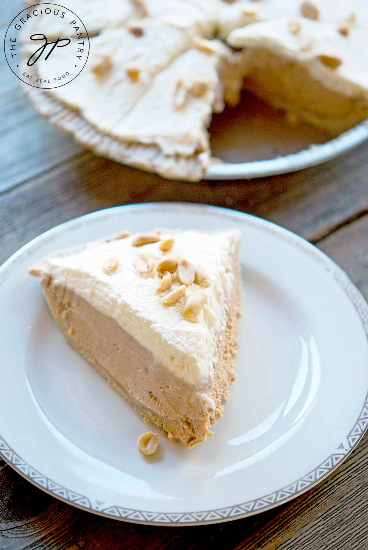 A slice of this Easy Peanut Butter Pie sits on a plate next to the pie it came from.