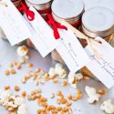 A row of spice bottles with labels tied to the bottles. Each bottle is filled with one of these Homemade Popcorn Seasoning Recipes