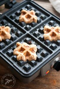 Just cooked waffle iron cookies still sitting on a waffle iron.