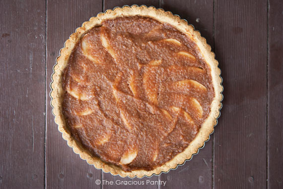 An overhead view of a whole Pear & Apple Tart on a wooden surface.