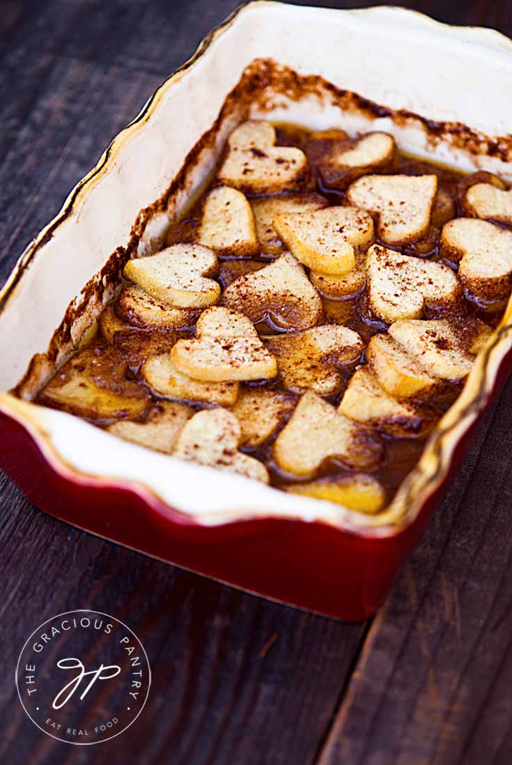 A side view of these heart-sharped, Maple Baked Sweet Potatoes sitting in a casserole dish.