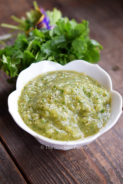 Clean Eating Salsa Verde in a white bowl with a bunch of fresh cilantro sitting behind it.