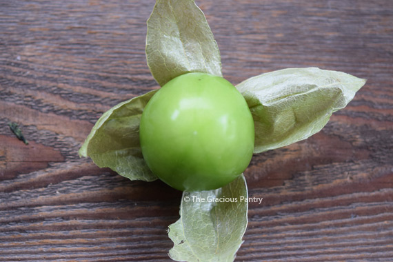 A single tomatillo with the husk pulled back looks like a star with the tomatillo still attached and sitting on top.