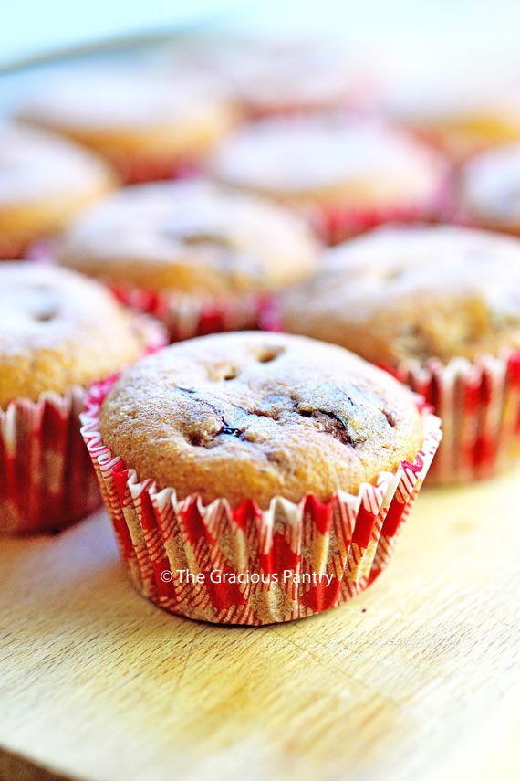 A close up shot of these Clean Eating Lunchbox Muffins lined up on a cutting board. Each muffin has a red and white checkered paper liner.