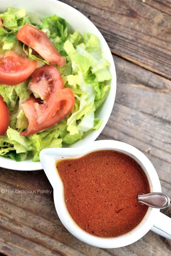 homemade French dressing in white dish next to healthy garden salad